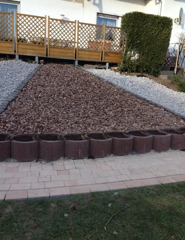Kiesfläche mit Palisadeneinfassung und gepflastertem Weg
